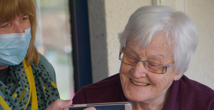 A carer holding a smart phone for her client