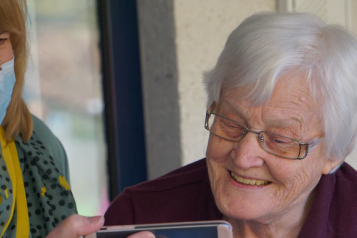 A carer holding a smart phone for her client