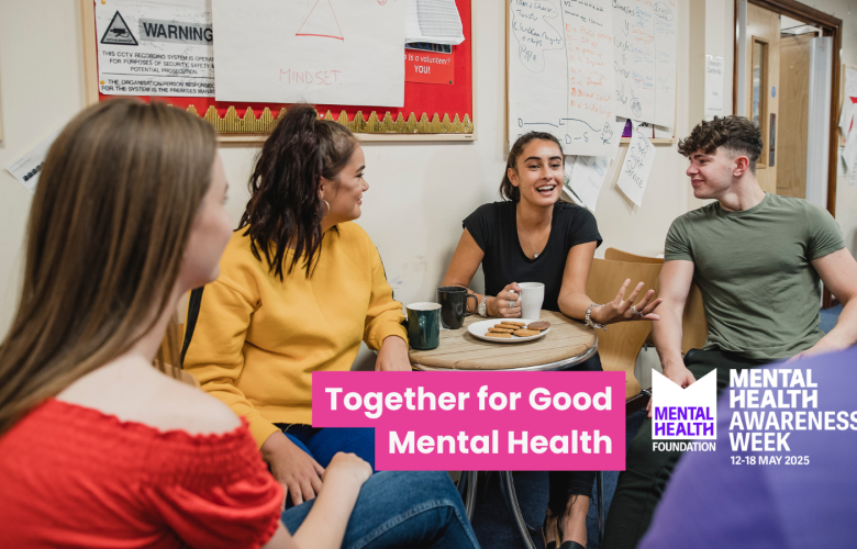 A group of young people sat around a table having tea and biscuits