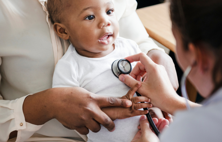 A photo of a baby being held by a parent as a doctor checks their heartbeat