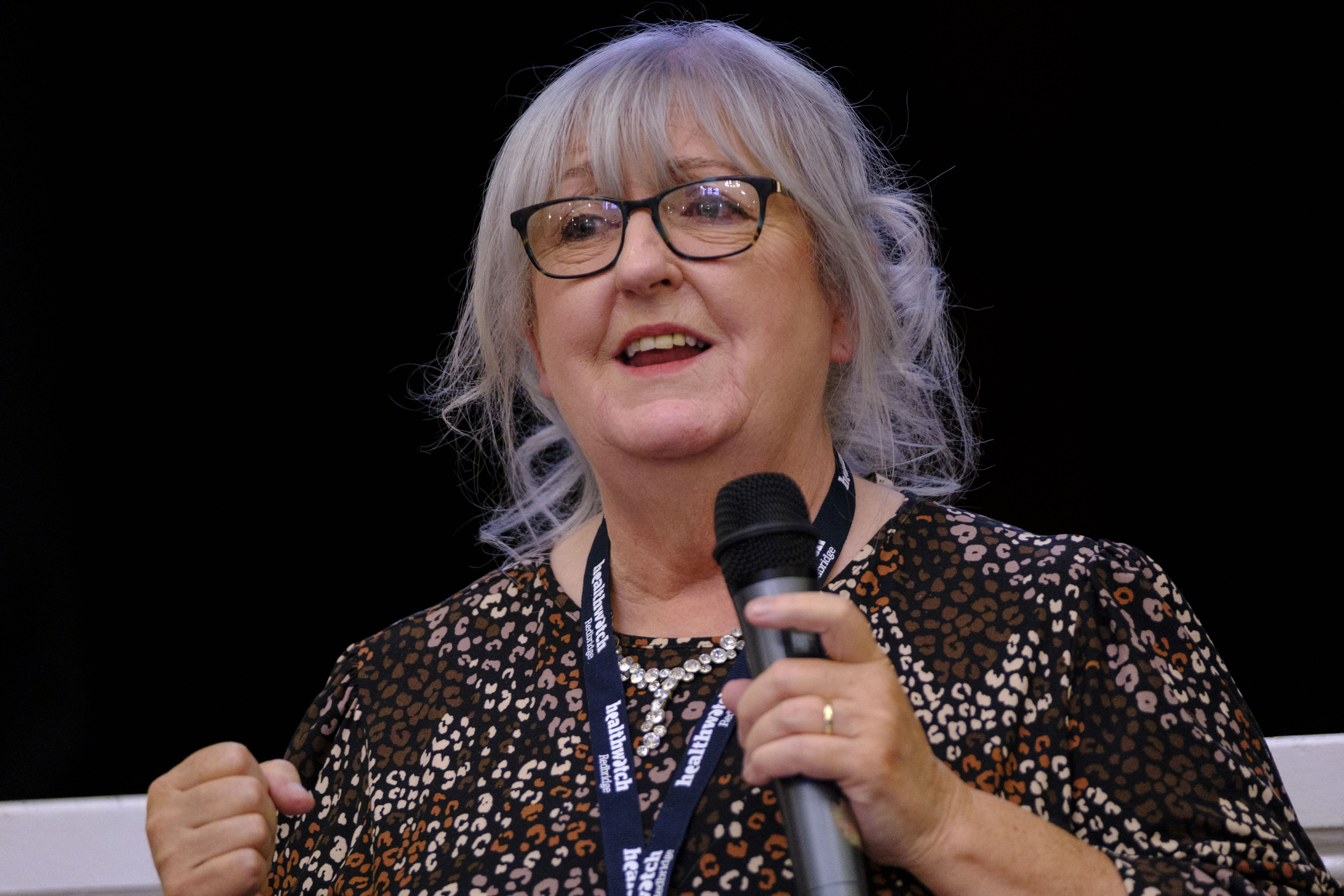 A photo of a woman holding a microphone as she delivers a speech.