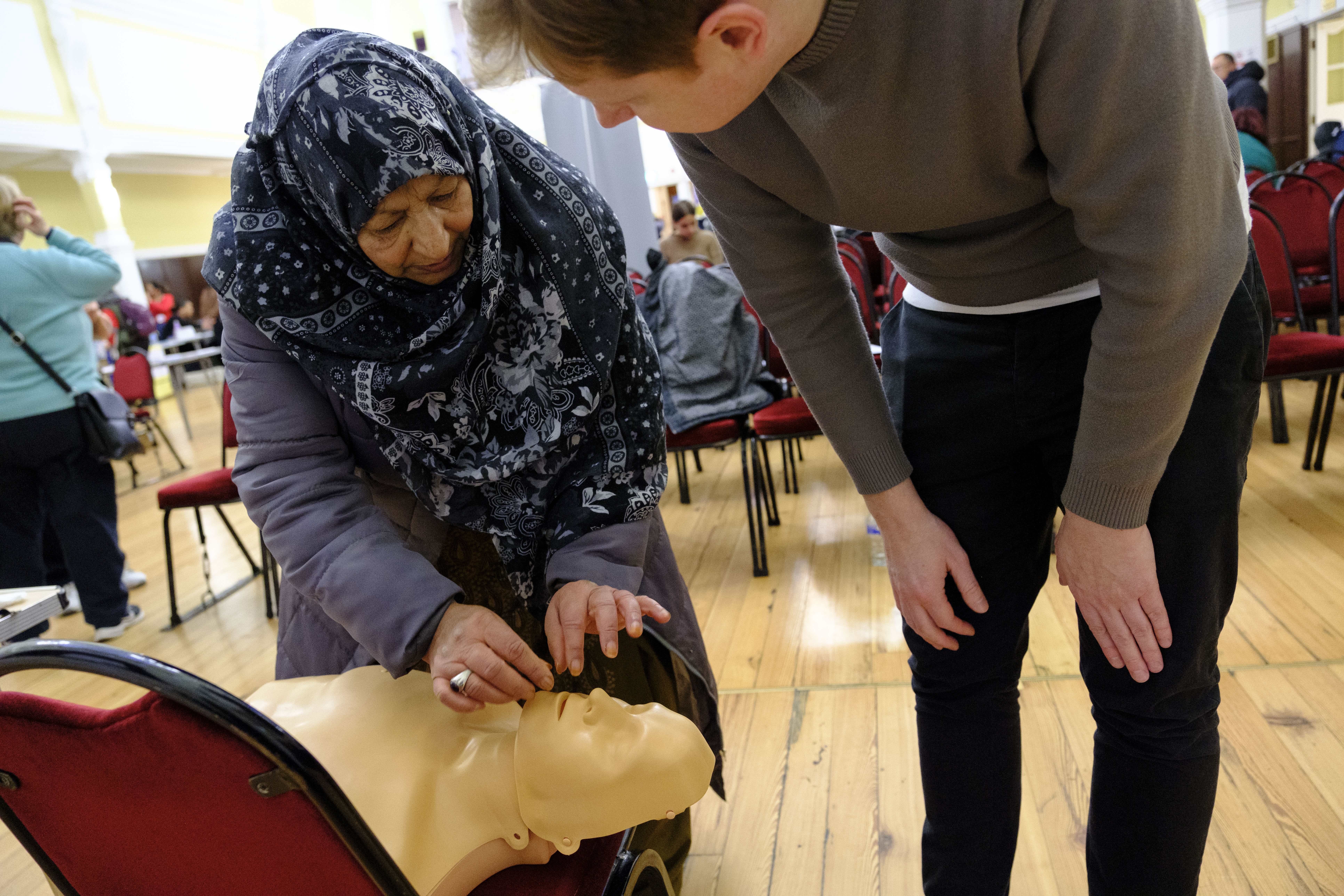 A man and a woman go through CPR training on a dummy. 