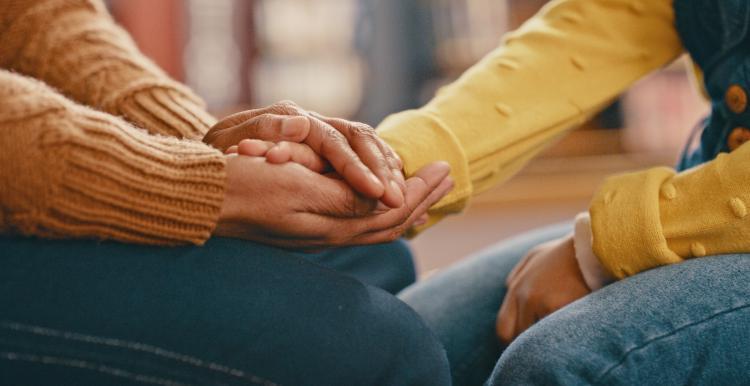 A close up photo of someone holding another person's hands in a supportive manner