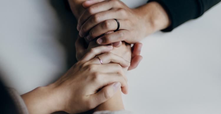 Two people holding hands in support