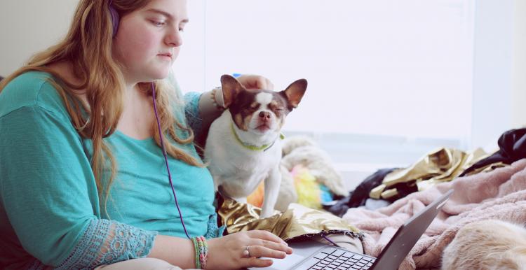 Young woman sat on the bed with a laptop