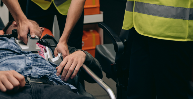 Paramedics in the back of an ambulance using a defibrillator on a man on a stretcher