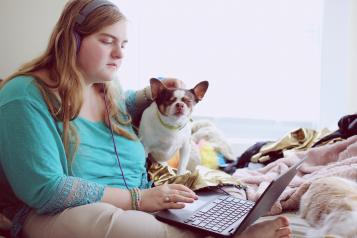 Young woman sat on the bed with a laptop