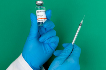 Hand holding and vaccine bottle and a syringe