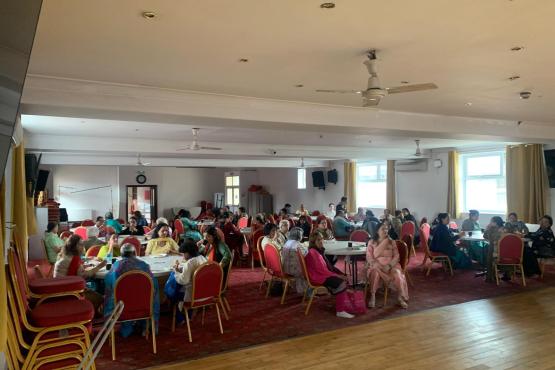 A photo of a large hall in a community centre full of people sat at round tables