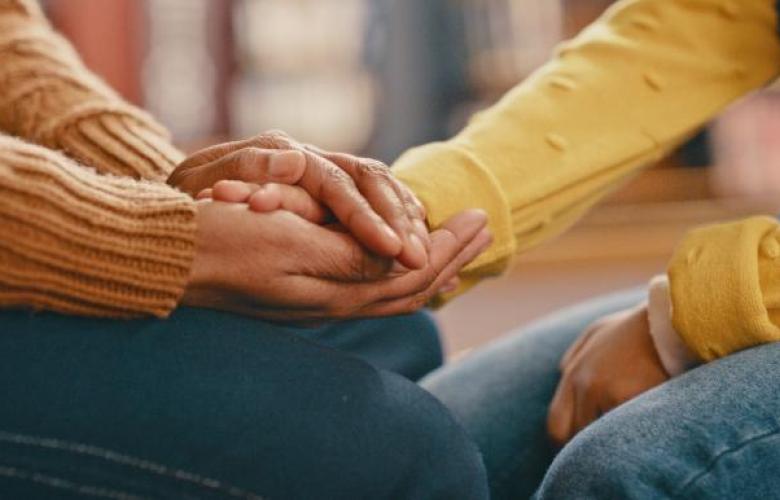 A close up photo of someone holding another person's hands in a supportive manner