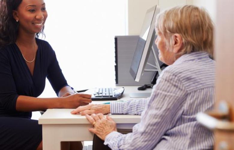 A photo of a patient with a doctor who is writing notes 